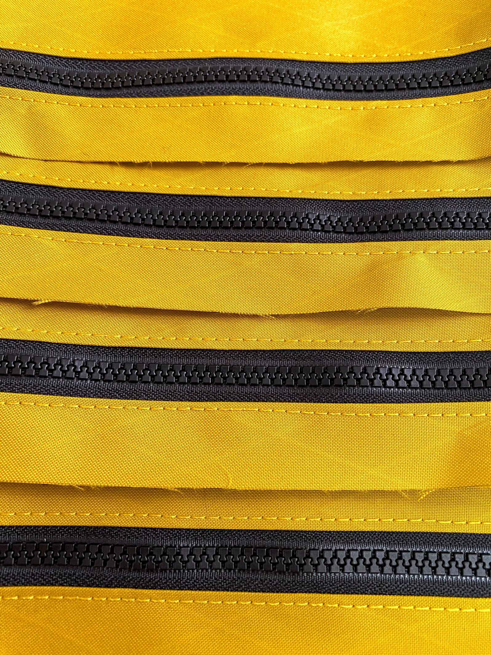 A stack of partially sewn bag zippers