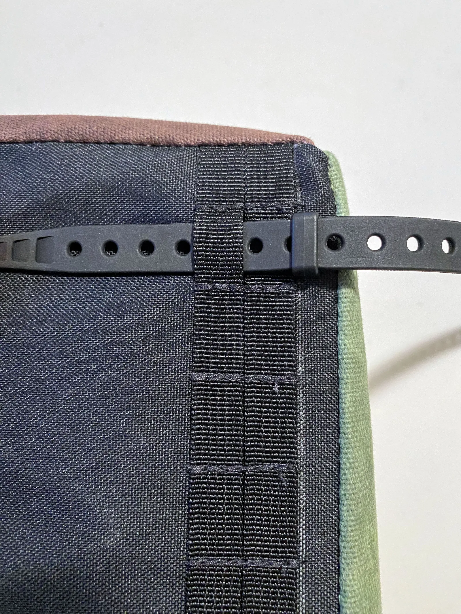 A strap going through webbing on the bottom of a rack bag