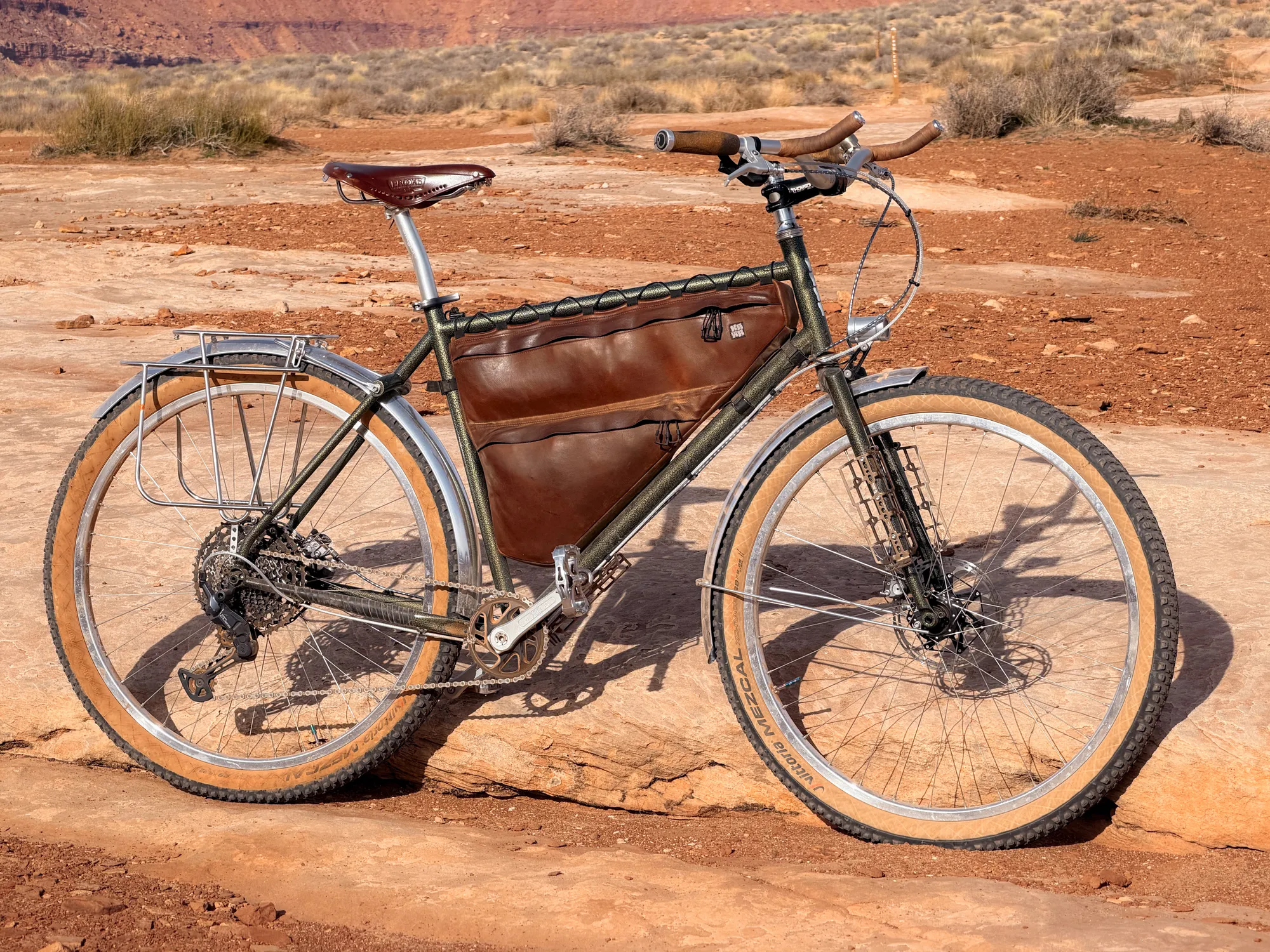Full bike shot showing the custom muted green paint against red desert terrain