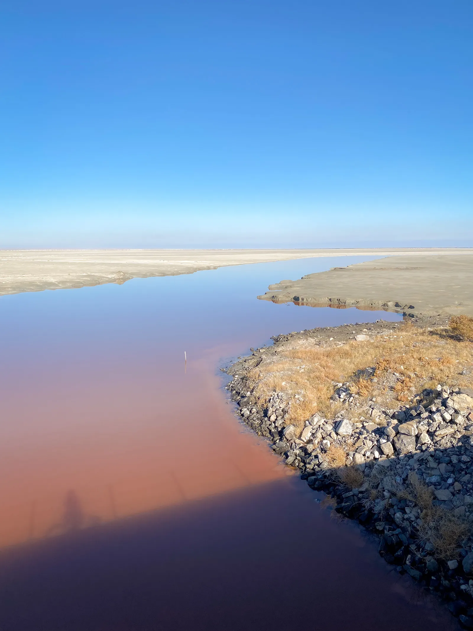 Blood-red pools and white salt flats on the lakebed seen from the causeway