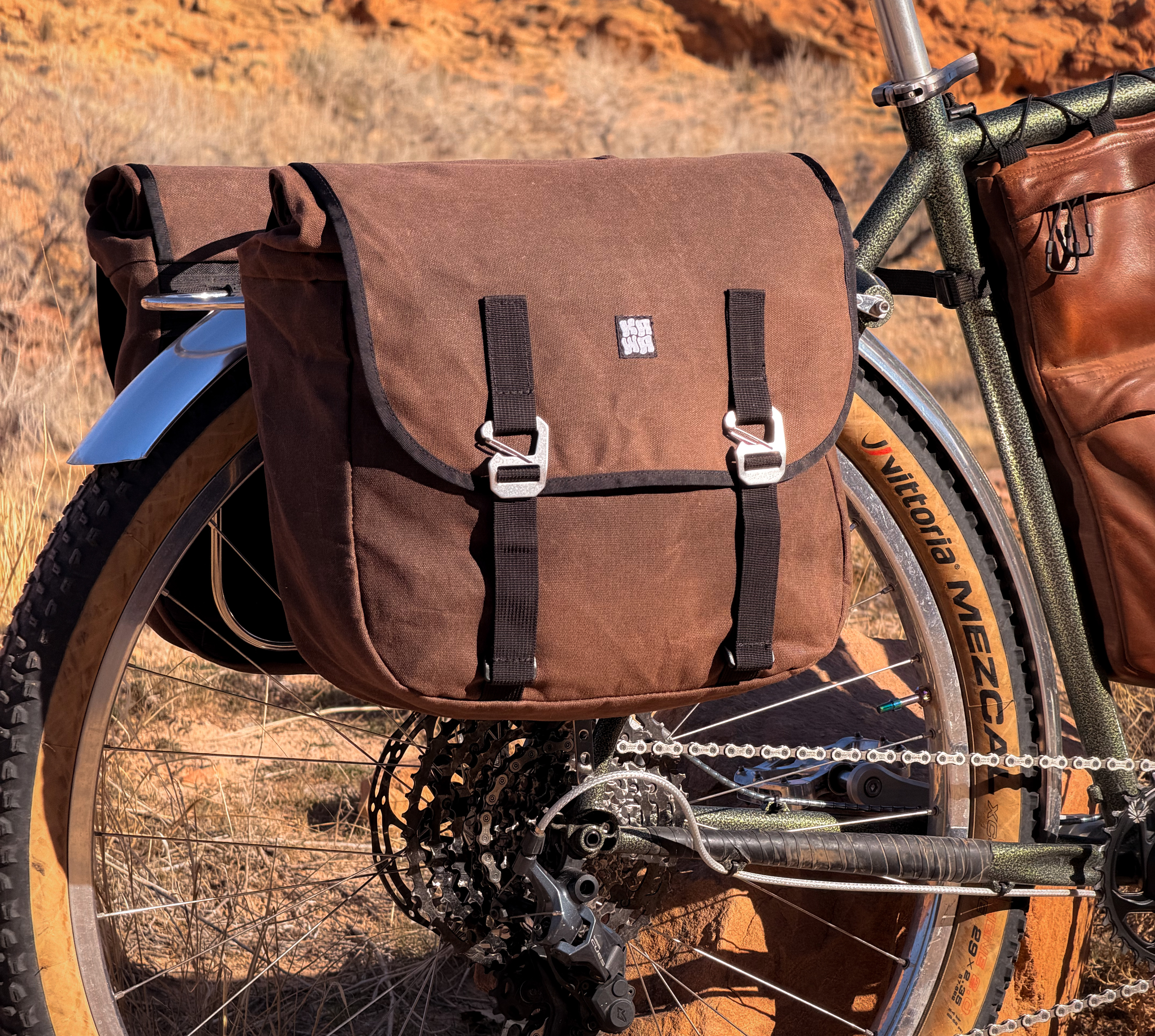 Close-up of the waxed canvas pannier with the leather framebag visible behind